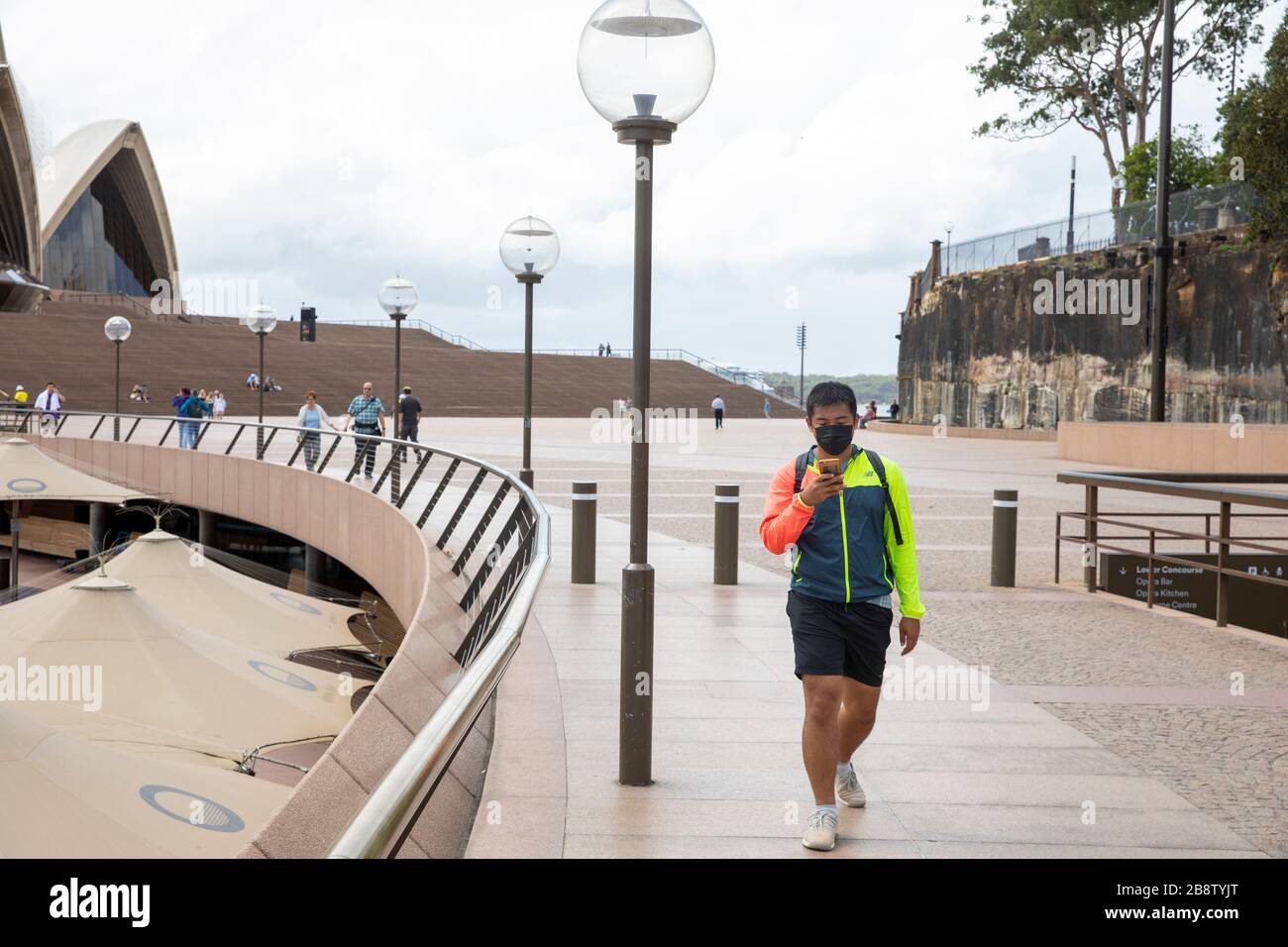 Centro di Sydney, Australia. Lunedì 23 Marzo 2020. Uomo asiatico che indossa una maschera facciale alla Sydney Opera House. Credit Martin Berry/Alamy Live News Foto Stock