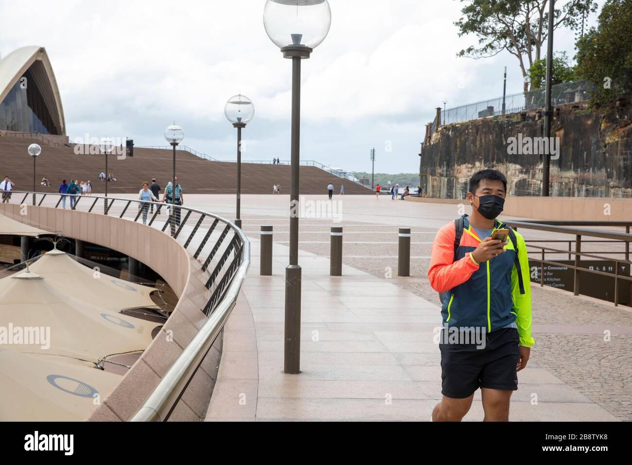 Centro di Sydney, Australia. Lunedì 23 Marzo 2020. Uomo asiatico che testava mentre indossava una maschera facciale a Circular Quay. Credit Martin Berry/Alamy Live News Foto Stock