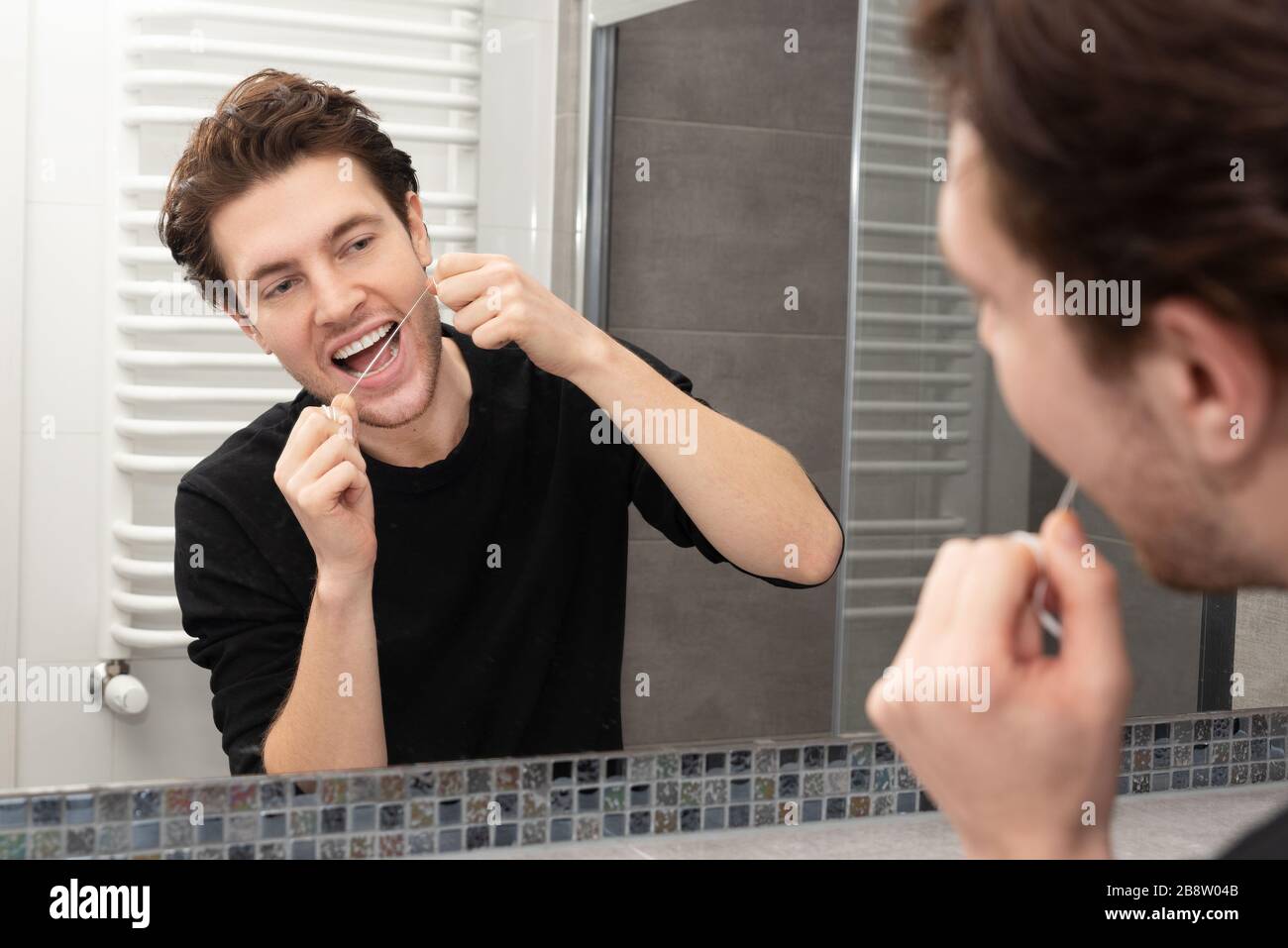 Uomo che usa filo interdentale in bagno. Concetto di salute dentale. Foto Stock