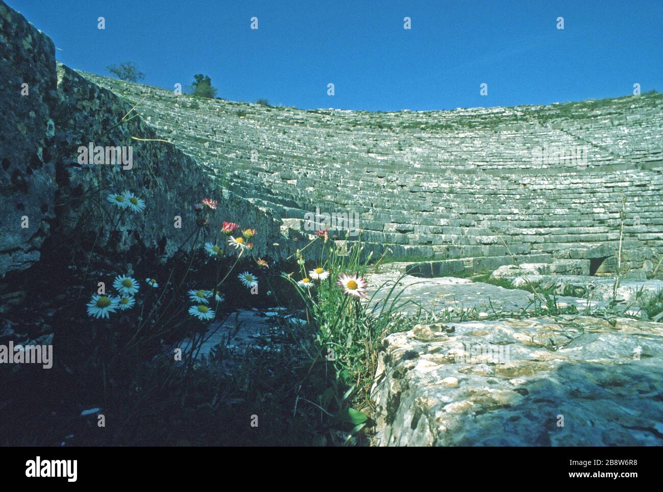 L'antico teatro greco di Dodoni, Ioannina, Epiro, Grecia, visto dal punto di vista degli artisti, mostra file curve di sedili in pietra che guardano verso il basso sul palco e scalano fino ad ogni livello. Cielo blu sullo sfondo. Dodoni è uno dei 15 teatri dell'antica Grecia, con lo status di patrimonio dell'umanità dell'UNESCO. Foto Stock