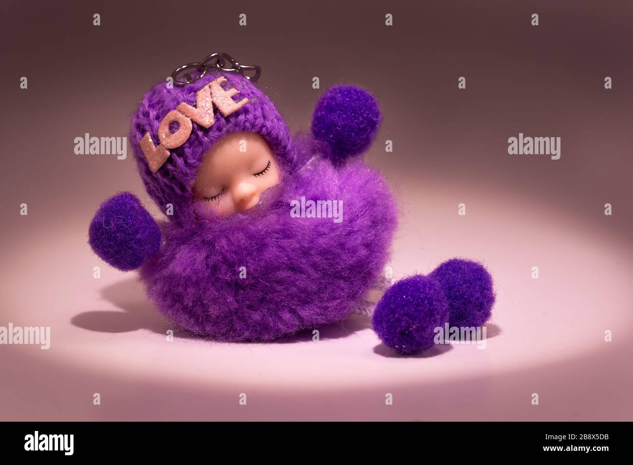 Amuleto, talismano un fascino di buona fortuna con iscrizione d'amore. Un soffice bambino viola addormentato. Spazio di copia Foto Stock