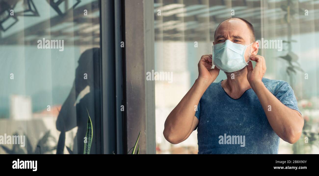 Uomo che indossa una maschera facciale monouso per evitare infezioni virali. Protezione antivirus Foto Stock