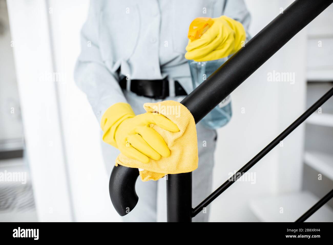 Donna con guanti protettivi disinfettante ringhiere per scale durante la pulizia a casa, vista ravvicinata sulle mani Foto Stock