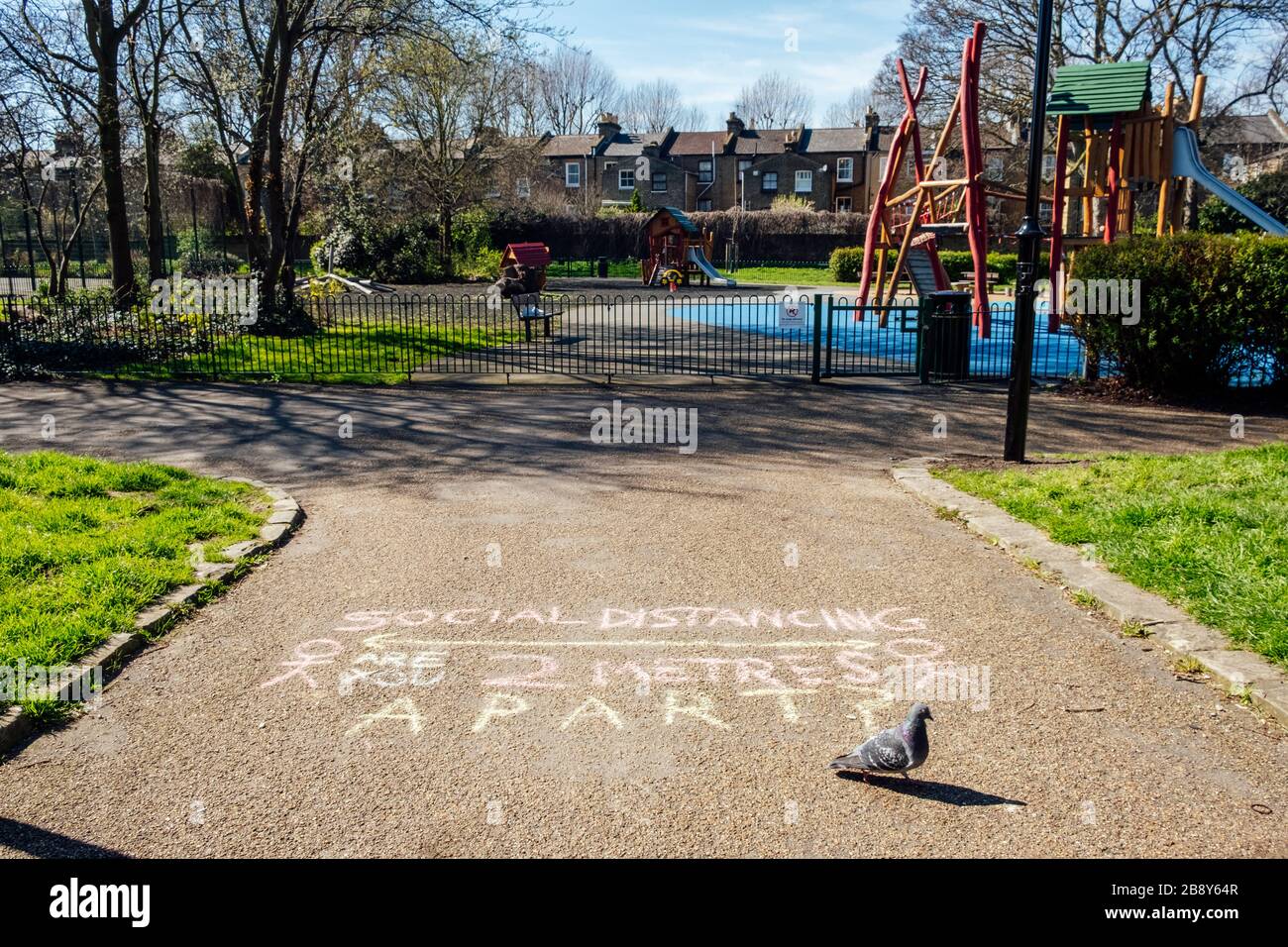 Brunswick Park, Camberwell, Londra, Regno Unito. 23 marzo 2020. Un messaggio in gesso sul percorso che ricorda alle persone di essere consapevoli del coronavirus, di aderire alle distanze sociali e fisiche e di tenere a 2 metri di distanza. Il parco giochi è stato anche chiuso, in quanto il governo rafforza la sua consulenza in materia di distanza sociale per ridurre la diffusione del virus Covid-19. Credit: Tom Leighton/Alamy Live News Foto Stock