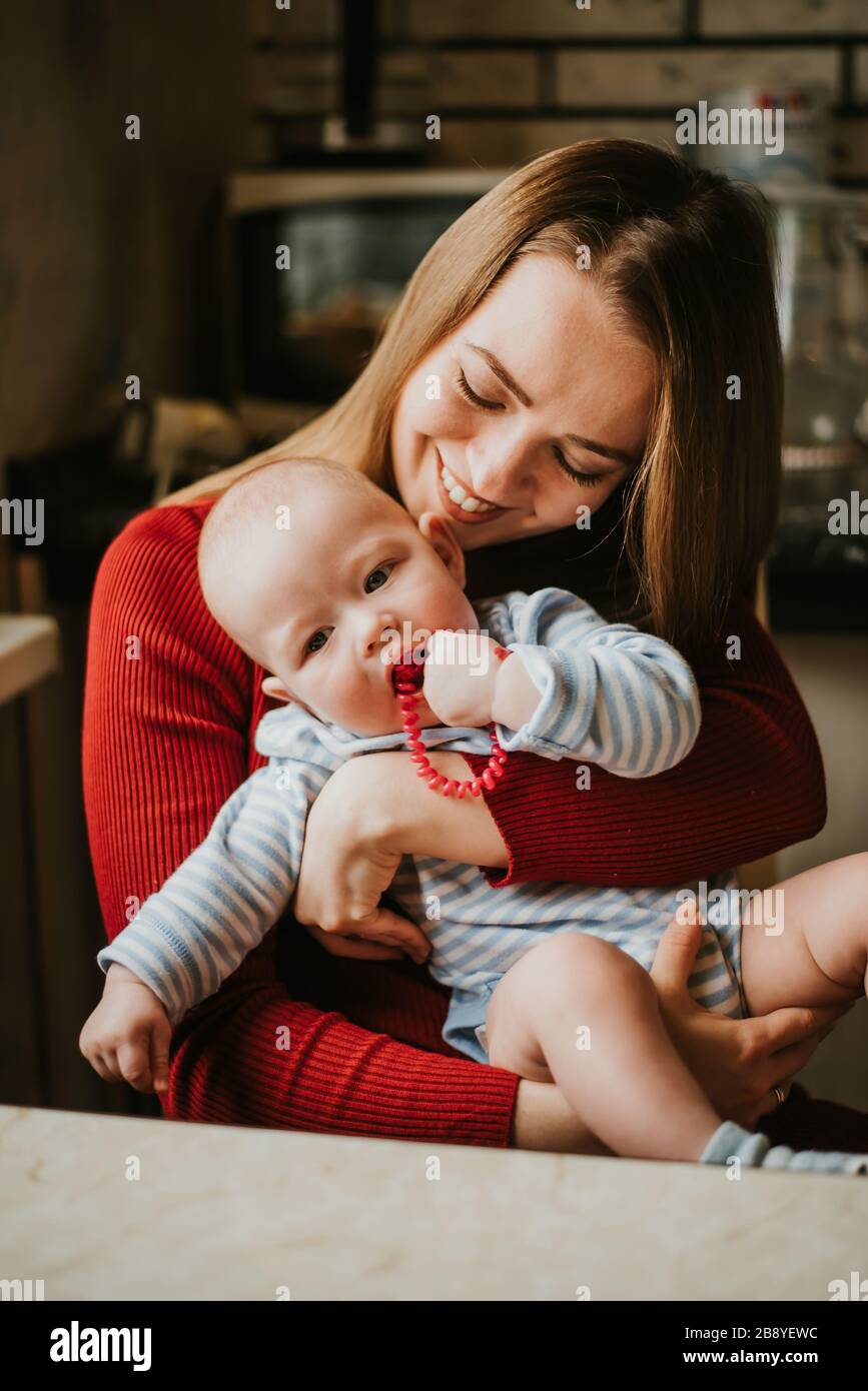 Una mamma tiene un bambino tra le braccia. Madre abbracci il suo bambino. Una giovane donna si diverte e gioisce con il bambino. Una ragazza innesti un bambino. Foto Stock