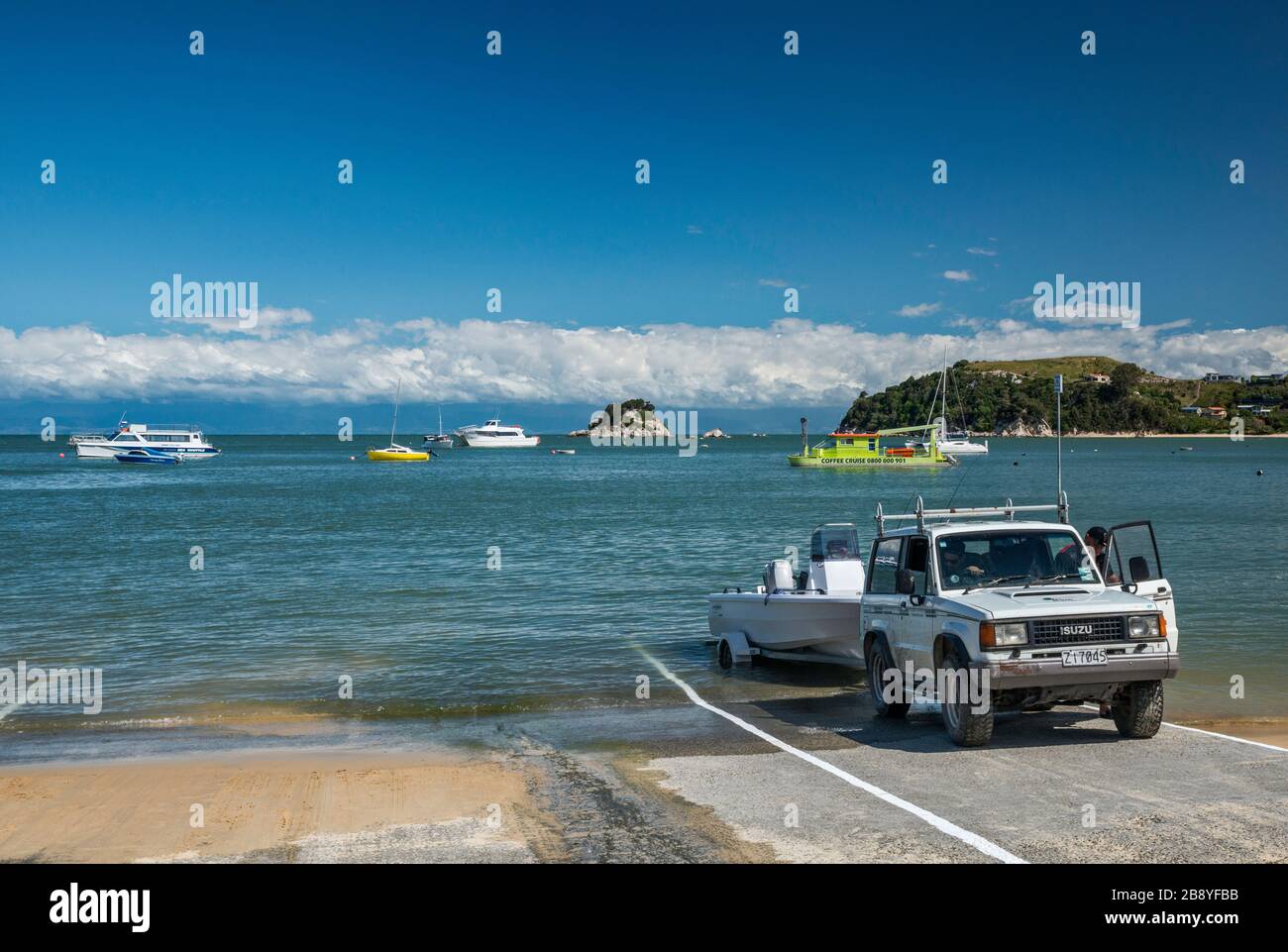 Veicolo che tira fuori una barca alla rampa sulla spiaggia di Kaiteriteri sopra la baia di Tasman, Kaiteriteri, il distretto di Tasman, l'isola del sud, la Nuova Zelanda Foto Stock