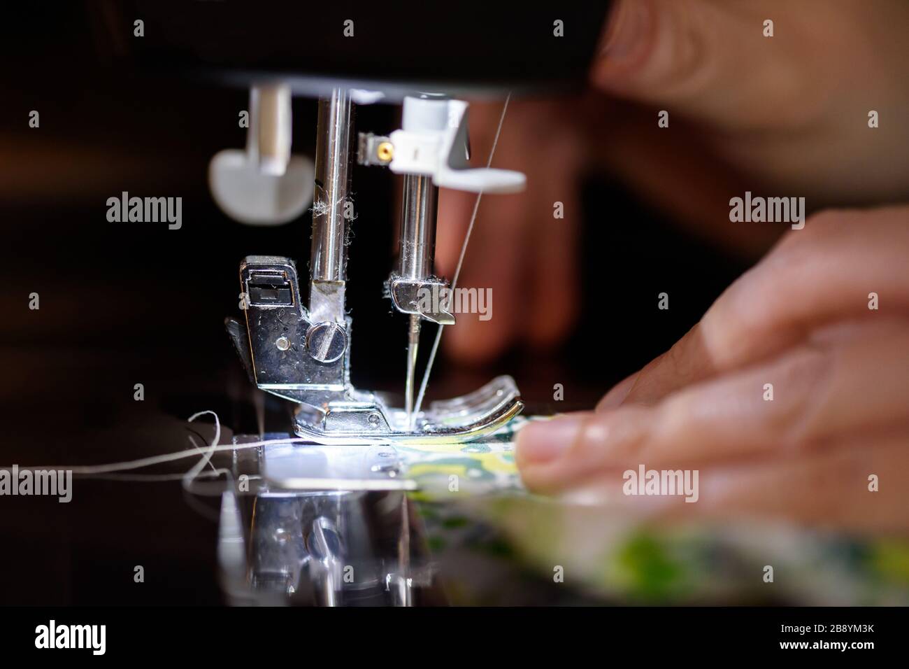 Stoffa per cucire a graffetta su una macchina per cucire, alla luce della  lampada da incasso. Ago in acciaio con chiusura del crochet Foto stock -  Alamy