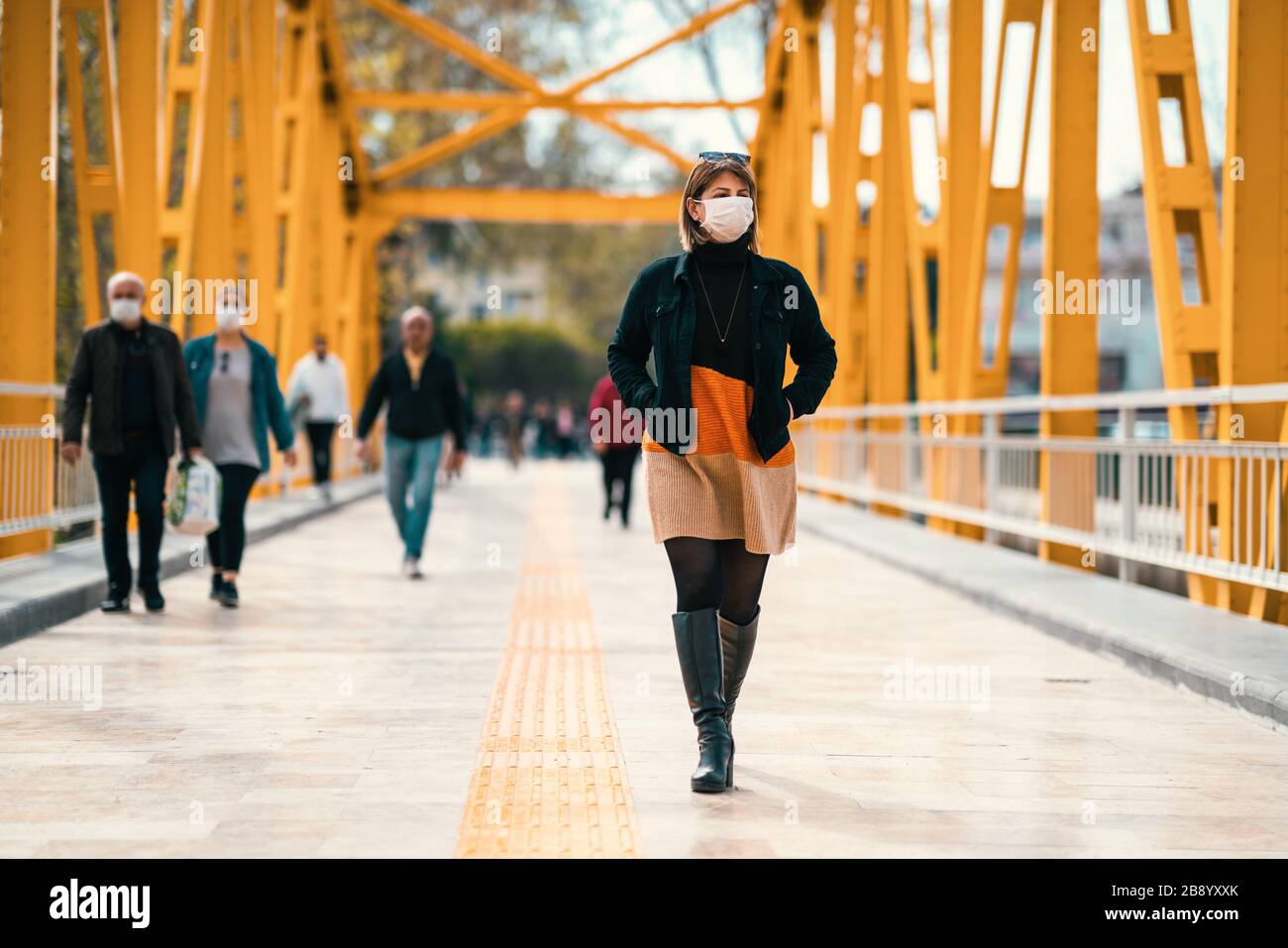 Una giovane donna sconsiderata cammina su strade affollate con una maschera in un periodo di quarantena a causa di pandemico pericolo globale Foto Stock