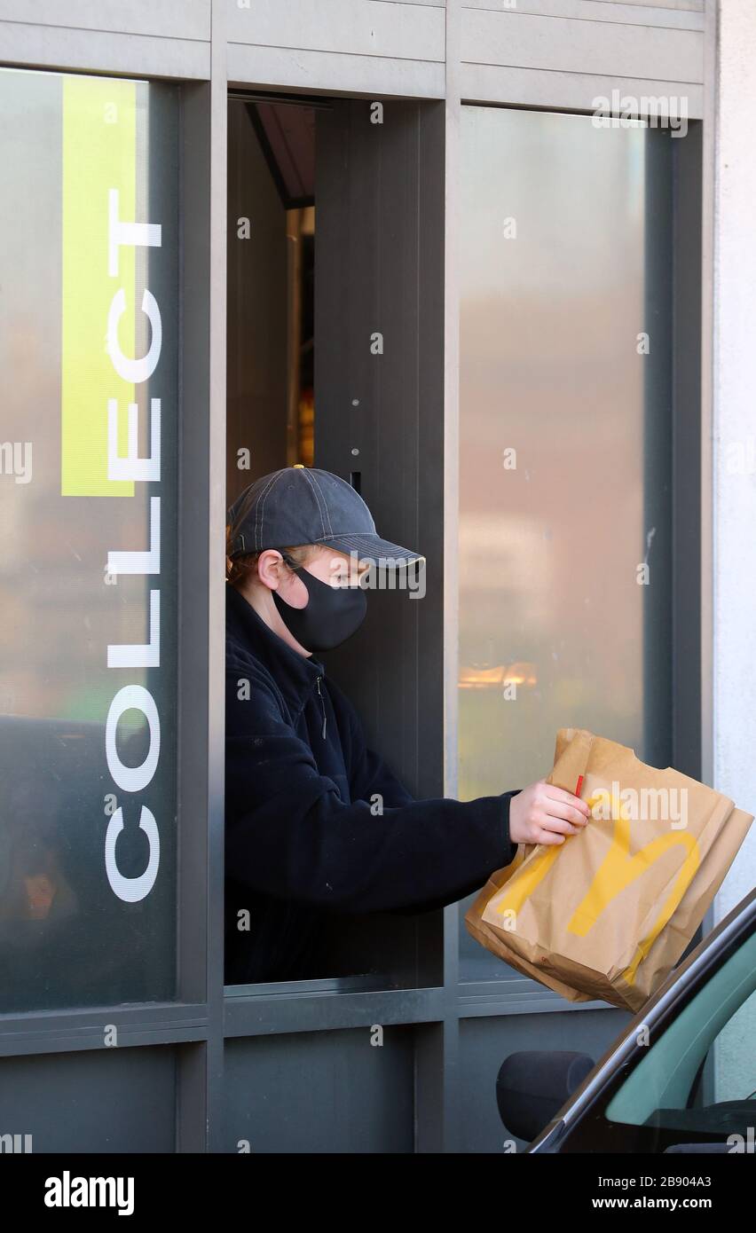 Un dipendente indossa una maschera per servire i clienti a un drive-thru McDonald vicino dover in Kent, in quanto è stato annunciato che tutti i loro ristoranti nel Regno Unito e in Irlanda chiuderanno entro le 19:00 di lunedì per proteggere la sicurezza dei loro dipendenti e clienti dal coronavirus. Foto Stock
