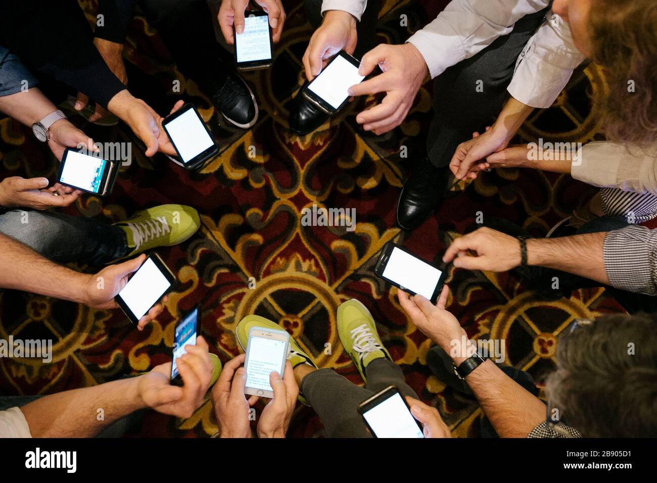 Mani di persone con i loro smartphone che lavorano durante una riunione. Foto Stock