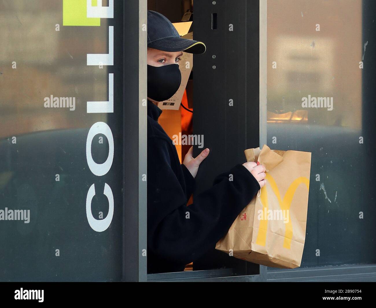 Un dipendente indossa una maschera per servire i clienti a un drive-thru McDonald vicino dover in Kent, in quanto è stato annunciato che tutti i loro ristoranti nel Regno Unito e in Irlanda chiuderanno entro le 19:00 di lunedì per proteggere la sicurezza dei loro dipendenti e clienti dal coronavirus. Foto Stock
