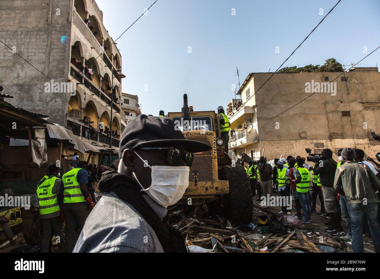 (200323) -- DAKAR, 23 marzo 2020 (Xinhua) -- UN uomo che indossa una maschera passa la scena dove i lavoratori della città demoliscono i negozi illegali nel mercato di Tilene a Dakar, Senegal, 22 marzo 2020. Per migliorare le condizioni sanitarie e ridurre la diffusione della COVID-19, il governo senegalese ha ordinato di pulire alcune zone che rappresentano minacce sanitarie nelle città. Finora il Senegal ha riportato 67 casi di infezione da COVID-19. (Foto di Eddy Peters/Xinhua) Foto Stock