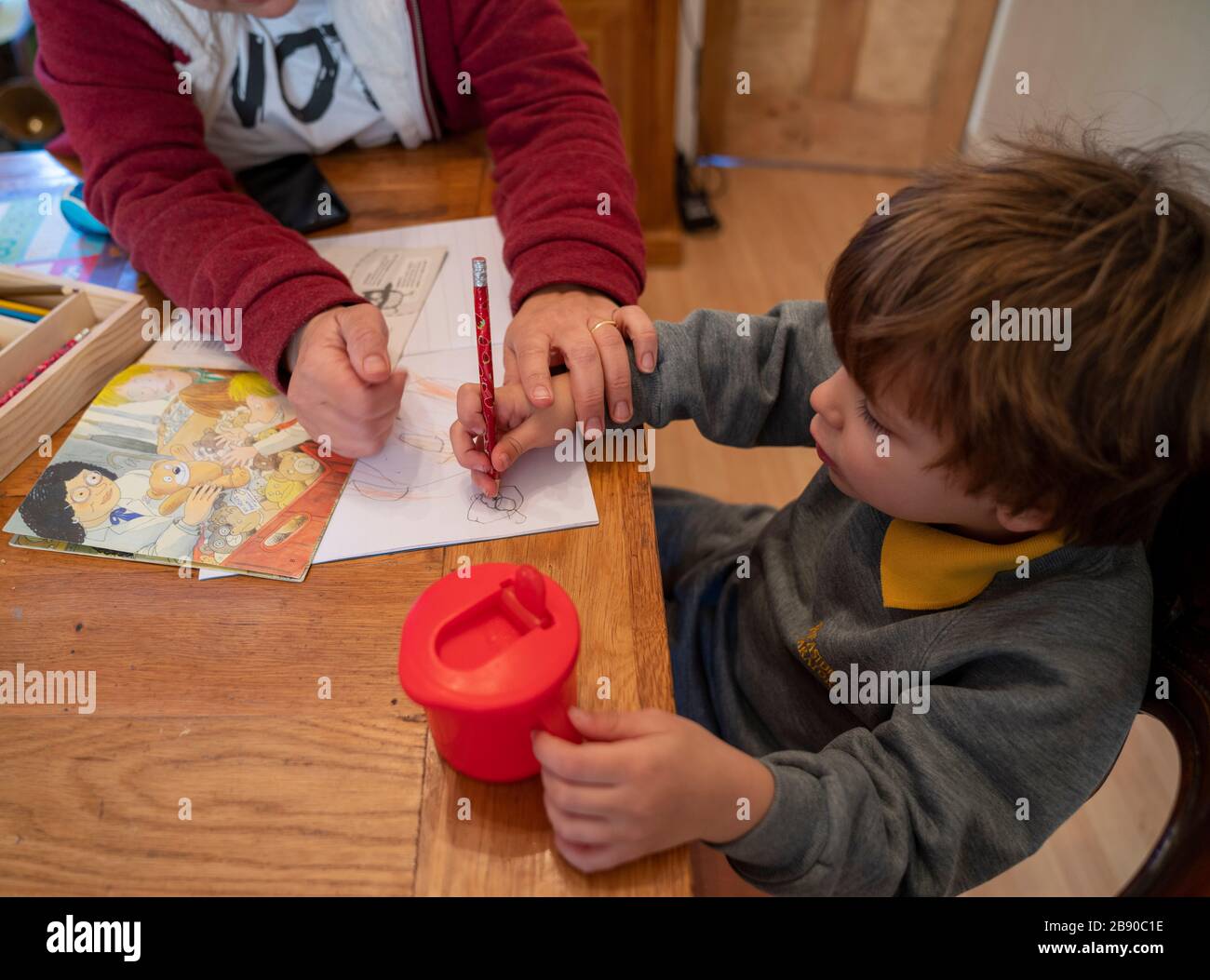 Benjamin, 3, pratica le lettere con la sua mamma a casa il primo giorno di scuola domestica dopo la chiusura delle scuole il venerdì a causa della pandemia di coronavirus. Foto Stock