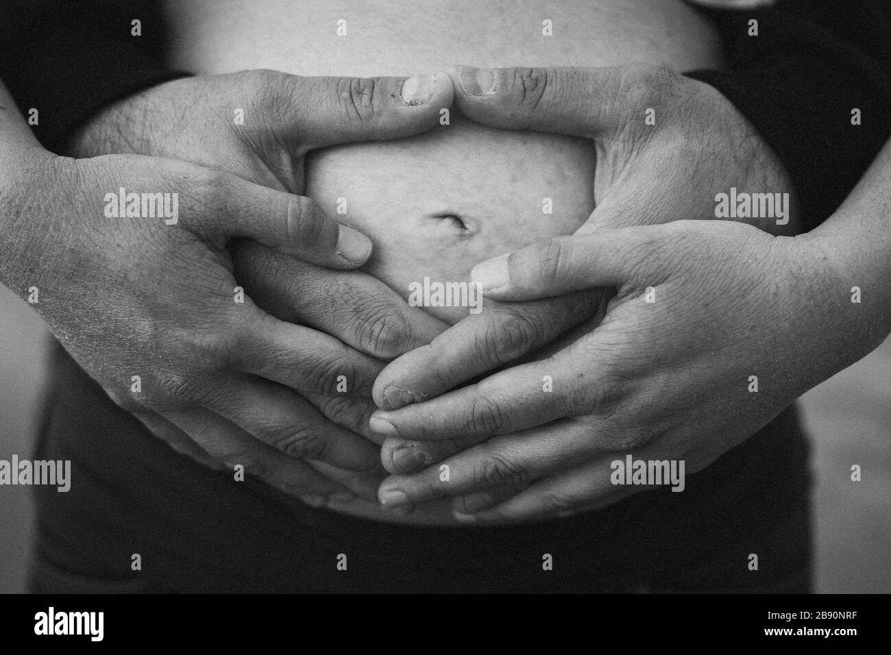 Mani di futuri genitori che tengono la sua pancia Foto Stock