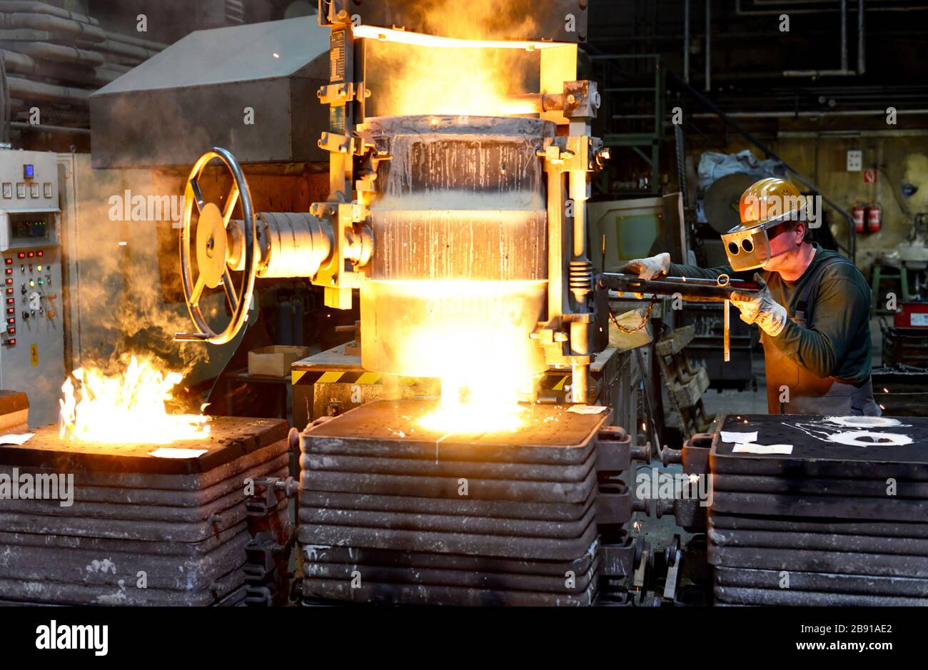 I lavoratori in un getto di fonderia di un pezzo di metallo - Sicurezza sul lavoro e il lavoro di squadra Foto Stock