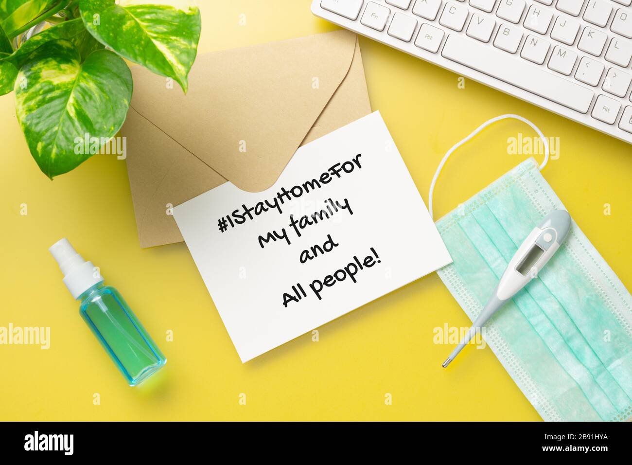 Rimando a casa per hashtag, pandemic incoronavirus prevenzione concetto campagna. Carta da lettera mockup con maschere facciali sul tavolo da ufficio giallo. N. IStayHo Foto Stock