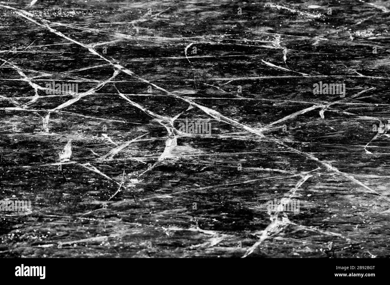 Copertura di ghiaccio del lago con molte crepe in stile bianco e nero Foto Stock