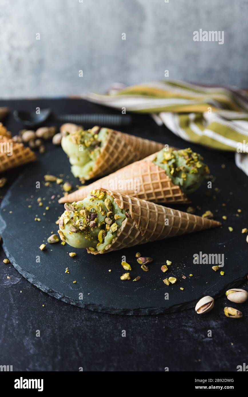 Primo piano di gelato al pistacchio in coni su sfondo nero. Foto Stock
