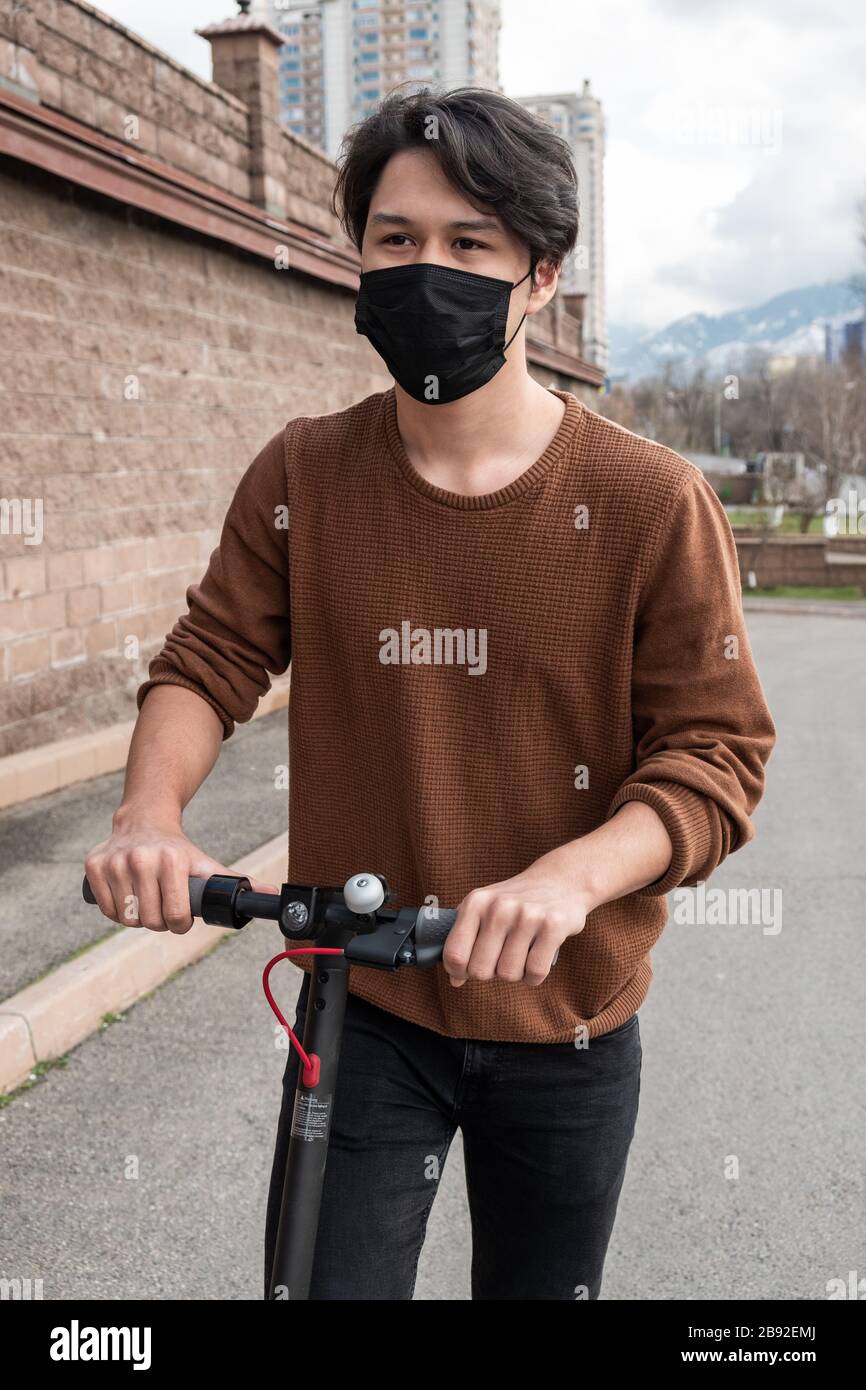 Giovane uomo che guida uno scooter in città Foto Stock