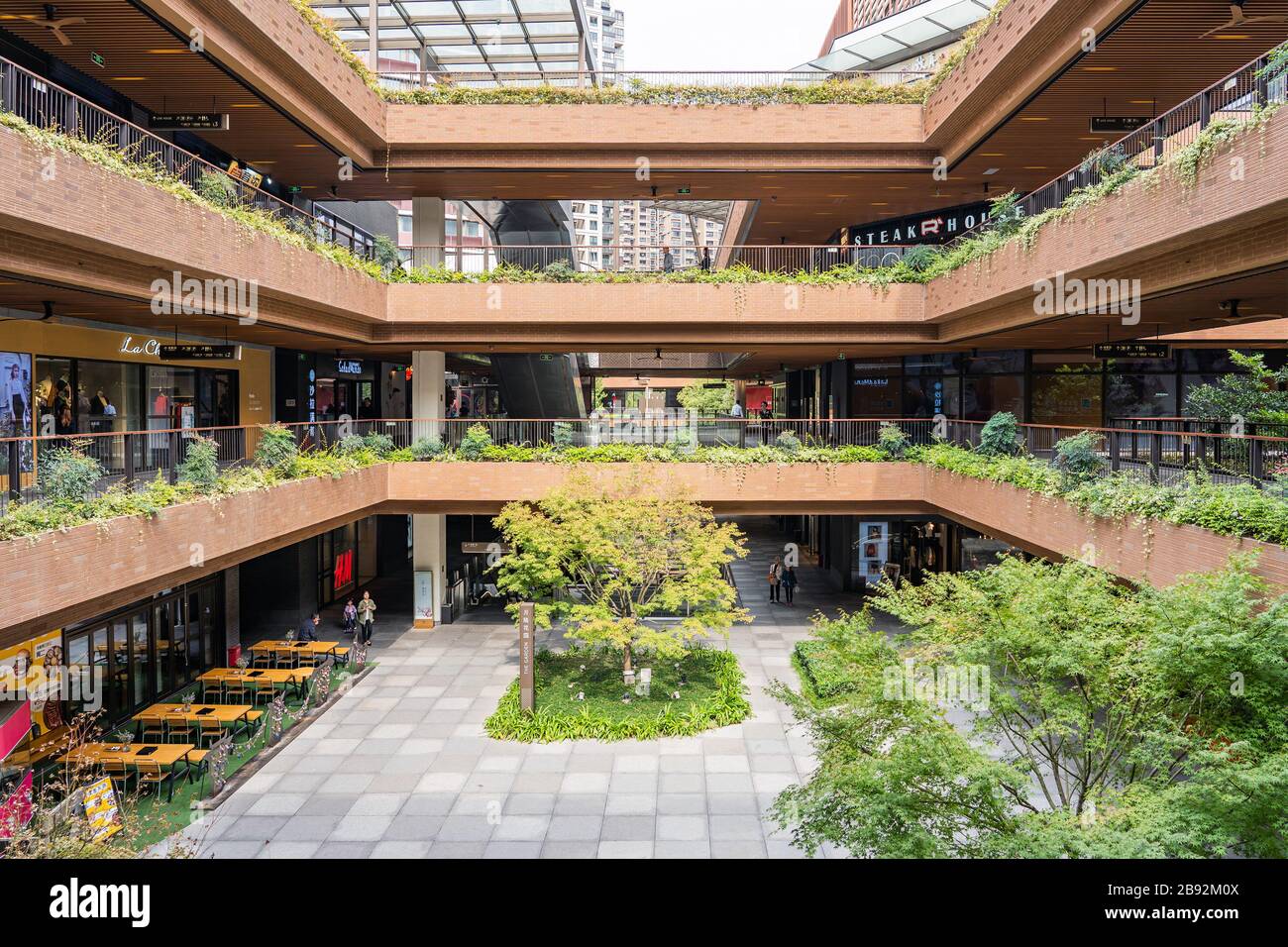 SHANGHAI, CINA - 10 NOVEMBRE 2018. Centro commerciale Ruihong Tiandi. Cortile esterno di un complesso di negozi con vegetazione lussureggiante. Giardino con passerella a Foto Stock