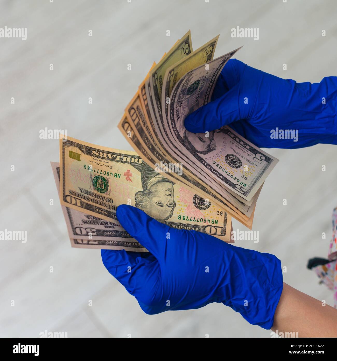 Mani in guanti per uso medico in possesso di un pacchetto di dollari. Il concetto di infezione su soldi, soldi sporchi, medicina paid, tasse di trattamento, tangenti, chirurgia illegale. Foto Stock