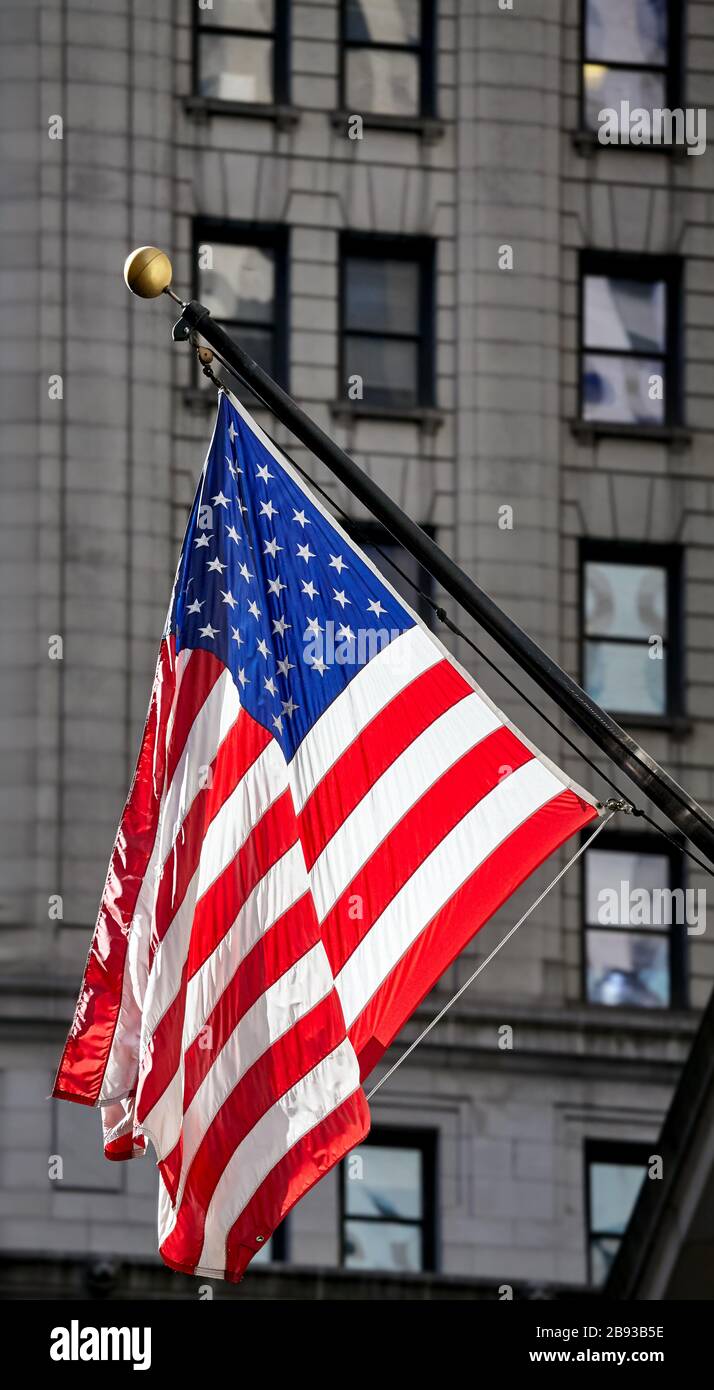 Bandiera americana con facciata edificio sullo sfondo, fuoco selettivo, New York City, USA. Foto Stock