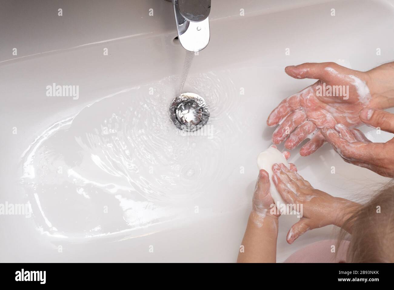 Il bambino e il padre si lavano le mani per proteggersi dal coronavirus Foto Stock