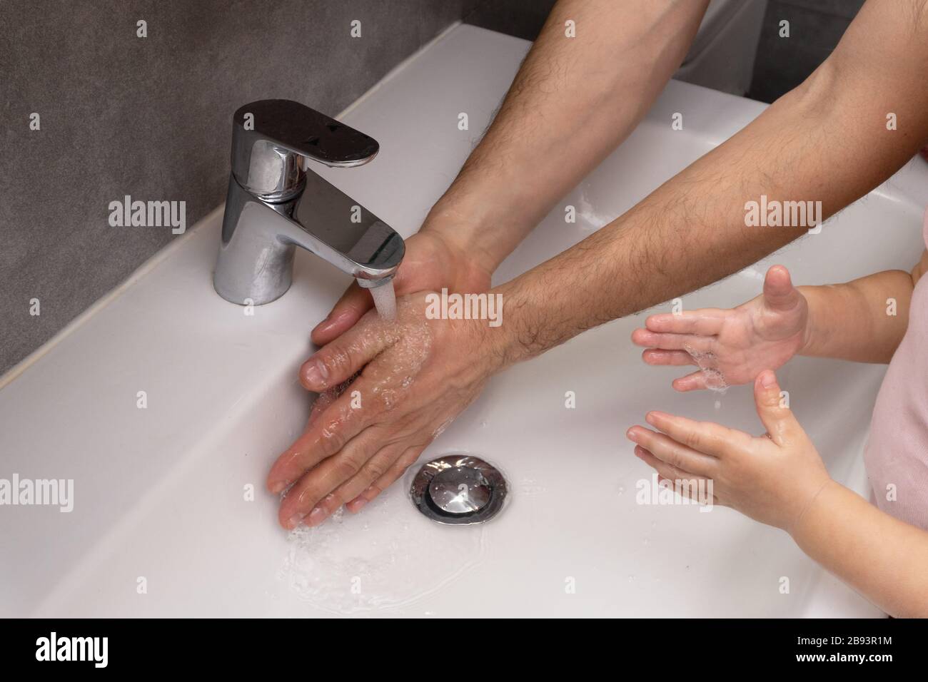 Padre insegna al bambino come lavarsi le mani correttamente Foto Stock