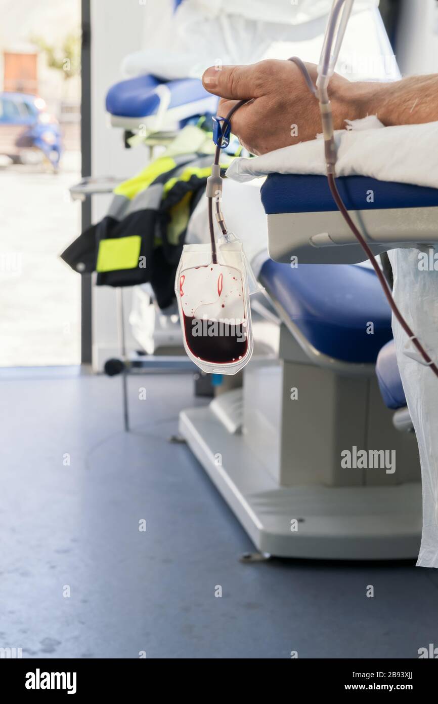 Una mano di donatore seduto su una poltrona in una banca di sangue mobile durante il prelievo di sangue. Donazione a sostegno degli ospedali durante il coronavirus Foto Stock