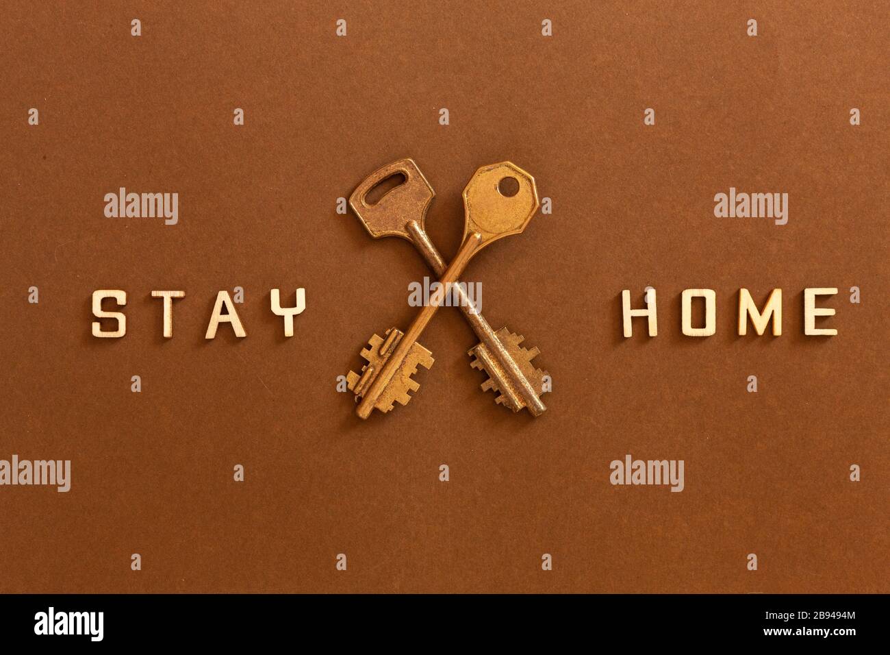 Le parole rimangono a casa fatte da lettere di legno e due chiavi, concetto di auto quarantena a casa come misura preventiva contro il virus corona Covid 19 outbr Foto Stock