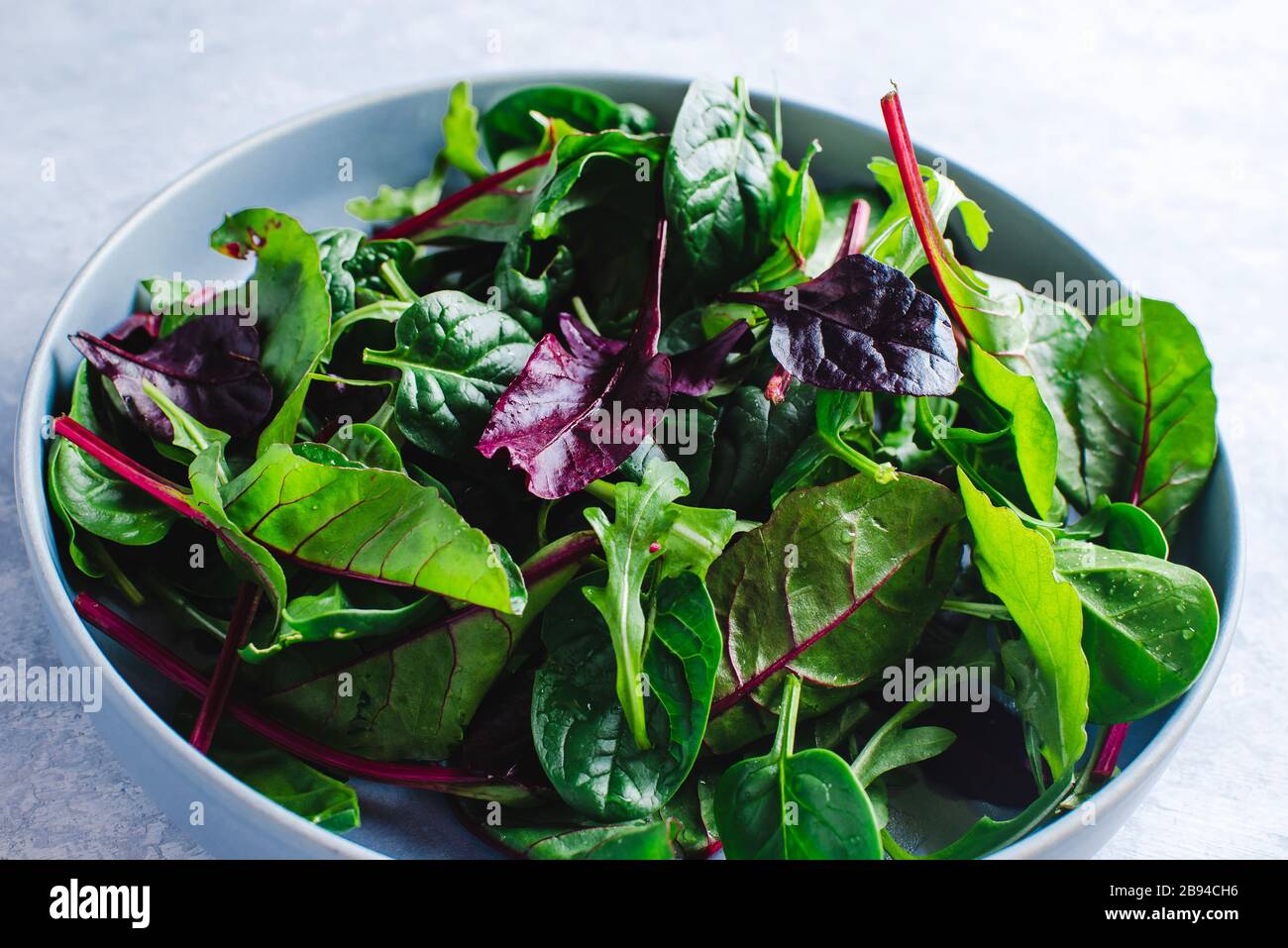 Insalata fresca con verdure miste (rucola, mesclun, mache) su sfondo di legno scuro primo piano. Cibo sano. Foto Stock