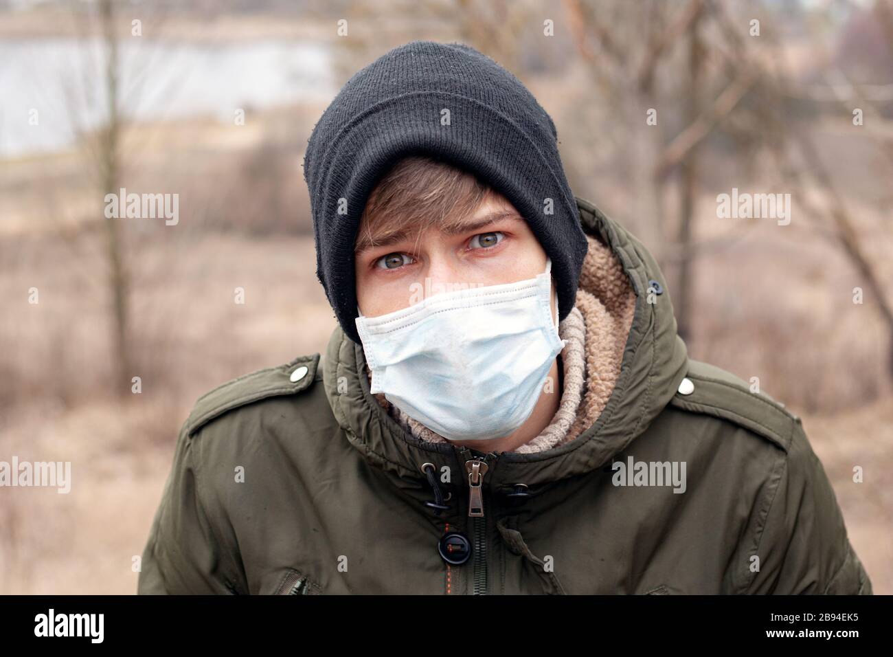 giovane uomo in maschera monouso medica si trova sulla strada. malattia virale respiratoria pandemica coronavirus influenza quarantena covid-19. Foto Stock