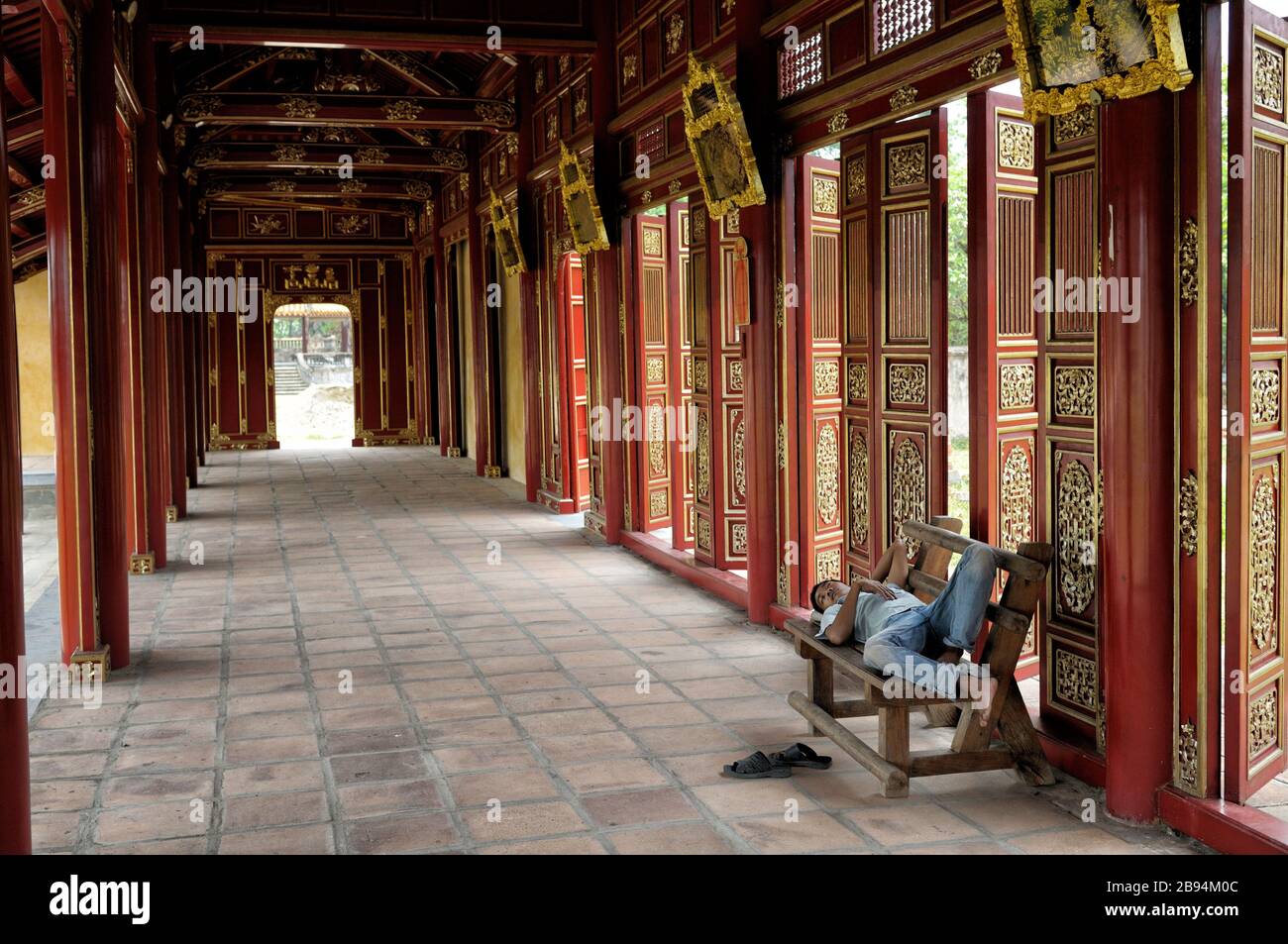 Uomo che prende un pisolino su una panchina alla città imperiale di Hue, Vietnam Foto Stock