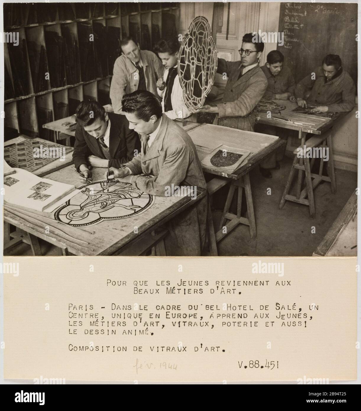 Fotografia propaganda apprendista in uno studio di vetro colorato, centro di apprendimento artigianato, Hôtel Salé, 3 ° arrondissement, Parigi Anonyme. «Photographie propagande : apprentis dans un atelier de vitrail, centre d'apprentissage des métiers d'art, hôtel Salé, 3ème circondario, Parigi». Pour que les Jeunes revivennent aux / Beaux Métiers d'Art / Paris - dans le cadre du bel Hotel de Salé, un / Centre, unique en Europe, apprend aux Jeunes, / les métiers d'art, vitraux, poterie et aussi le dessin animé. / Composition de vitraux d'art. Tigre au gélatino-bromure d'argent. Légende dactylographiée à l'encre Foto Stock