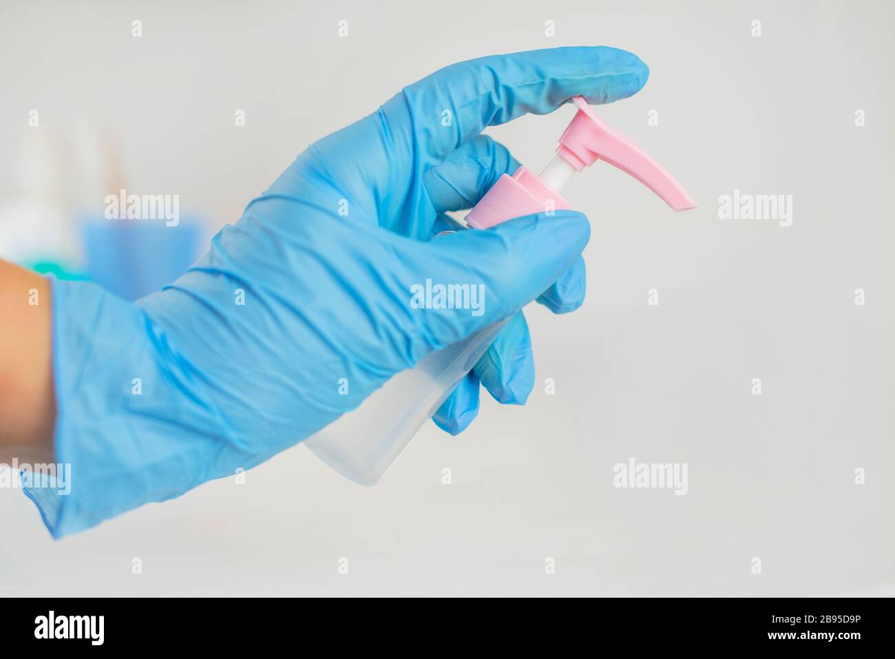 antibatterico agente protettivo antisettico nelle mani di una ragazza in guanti blu contro infezioni e germi Foto Stock