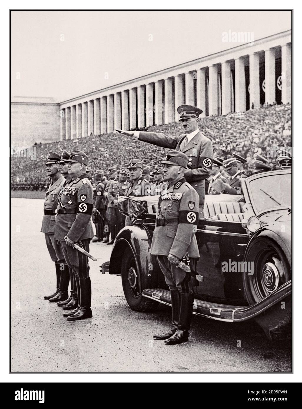 Vintage 1936 nazista Propaganda Norimberga Rally Germania Adolf Hitler, indossando swastika armband, dà Heil Hitler saluto al marzo passato del Reich Labor Service al Zeppelin Fields Nazi Party Rally riunione. Nella foto sono raffigurati Adolf Hitler, Konstantin Hierl, il ministro del Reich Rudolf Hess e il ministro del Reich Wilhelm Frick Foto Stock