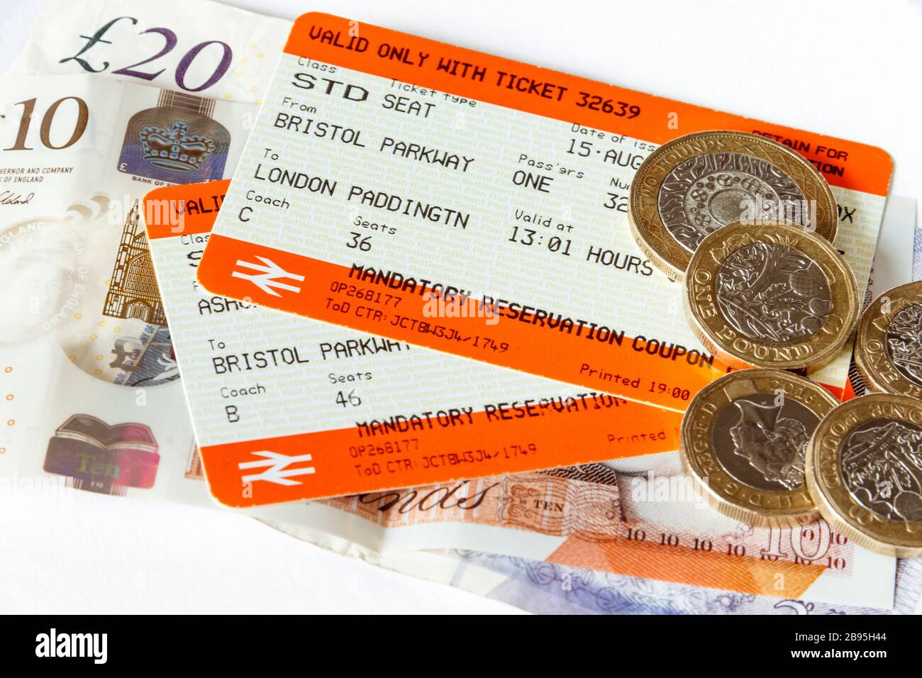 Due biglietti del treno (da Bristol Parkway a Londra Paddington), banconote e monete britanniche su sfondo bianco Foto Stock
