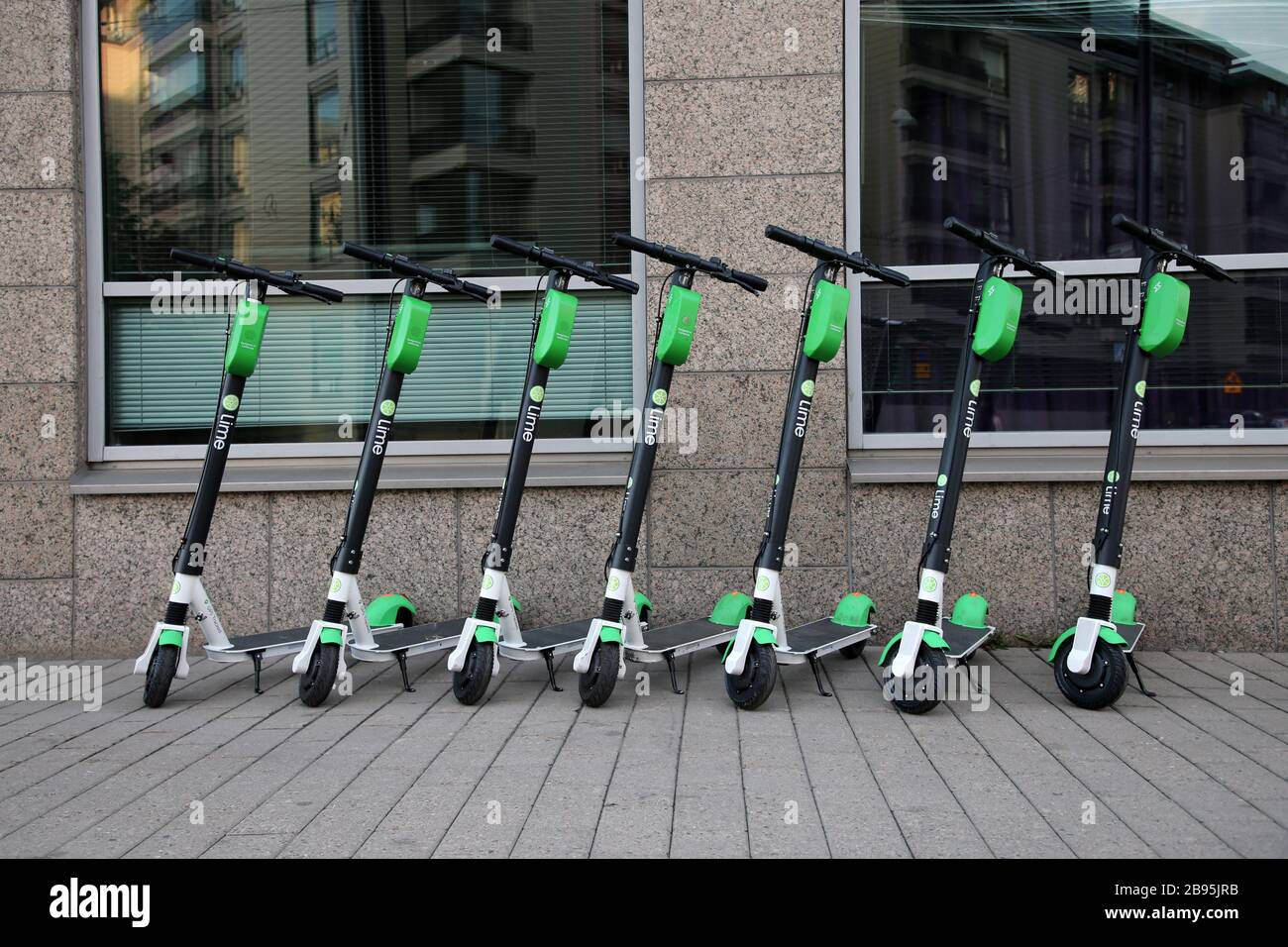 Molti scooter elettrici a noleggio Lime si sono allineati fotografati durante una giornata estiva di sole nel centro urbano di Helsinki. Modo di muoversi alla moda. Helsinki, Fi. Foto Stock