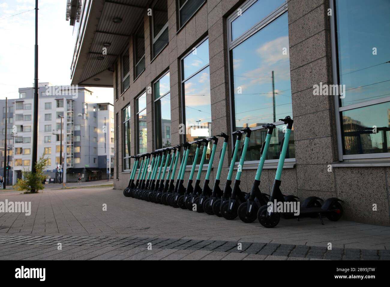 Molti scooter elettrici a noleggio Tier si sono allineati fotografati durante una giornata estiva di sole nel centro urbano di Helsinki. Modo di muoversi alla moda. Helsinki, Fi Foto Stock