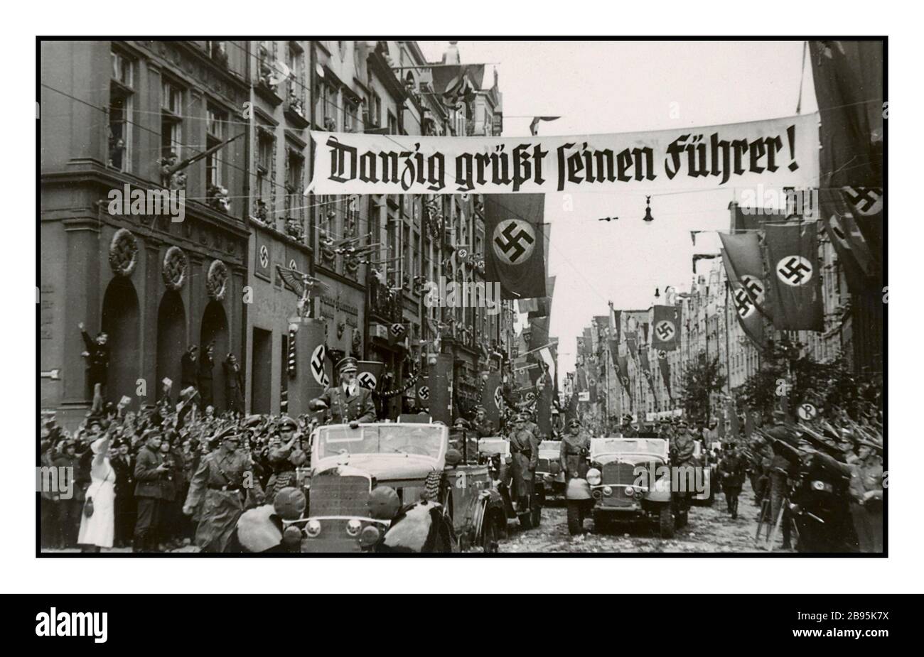 Invasione della Polonia vintage 1939 Adolf Hitler in Mercedes a bordo di un'auto salutata da folle estatiche che sventolano facendo saluta Heil Hitler durante l'invasione di Danzig (Danzica) nel 1939 POLONIA SETTEMBRE 01: Dopo l'invasione della Polonia all'inizio di settembre 1939, Adolf Hitler parata con bandiere di svastika nelle strade della città di Danzica Polonia Foto Stock
