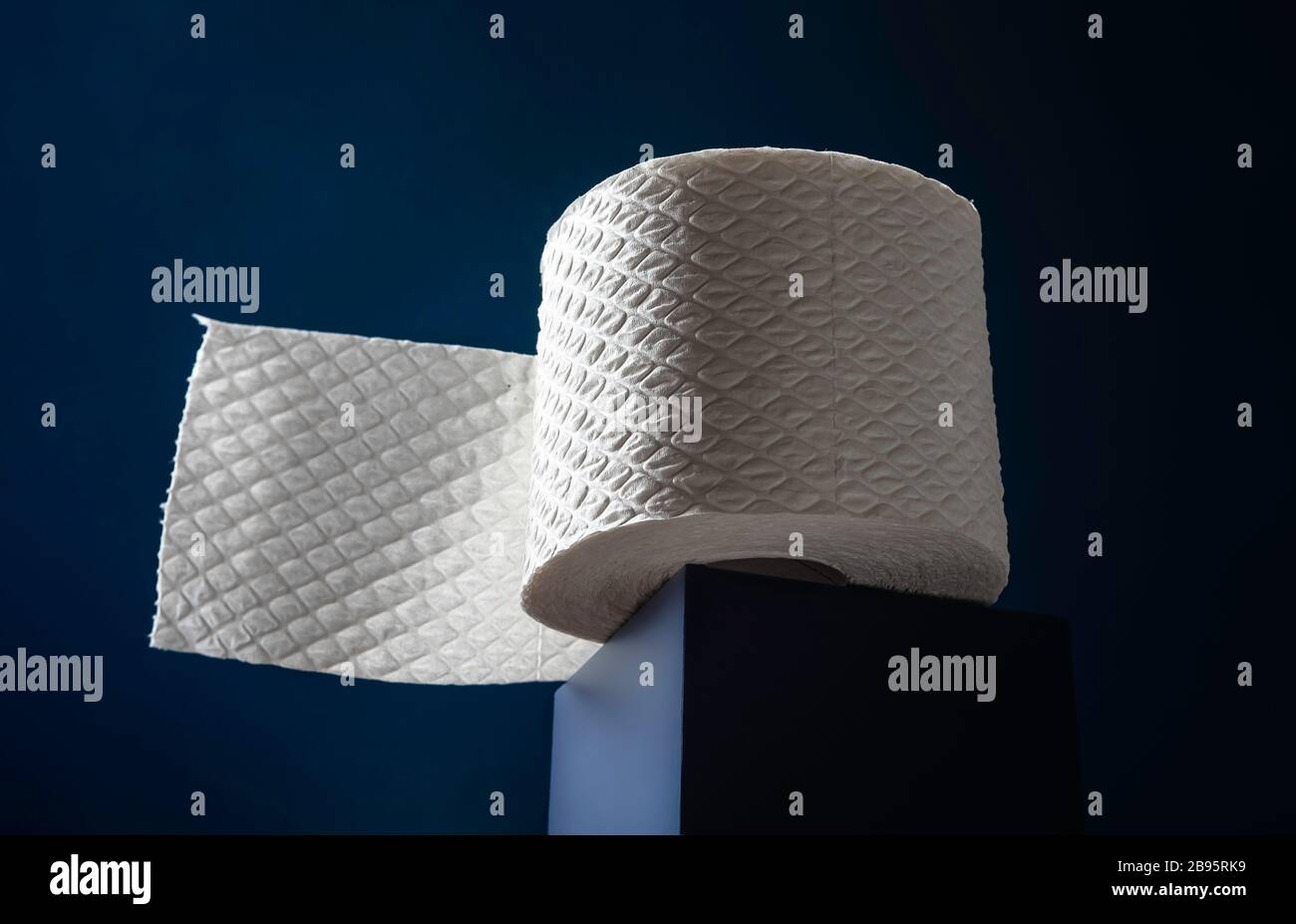 Rotolo di carta igienica bianca su un cubo blu. Carta igienica morbida, vista ad angolo basso. Foto Stock