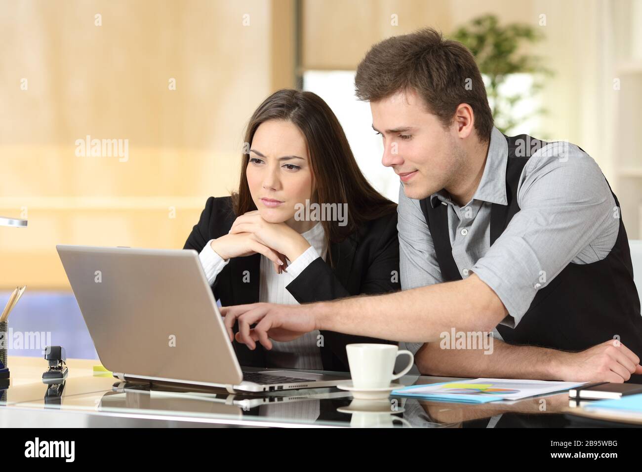 Due colleghi che lavorano insieme per controllare i contenuti dei notebook e parlarne in ufficio Foto Stock