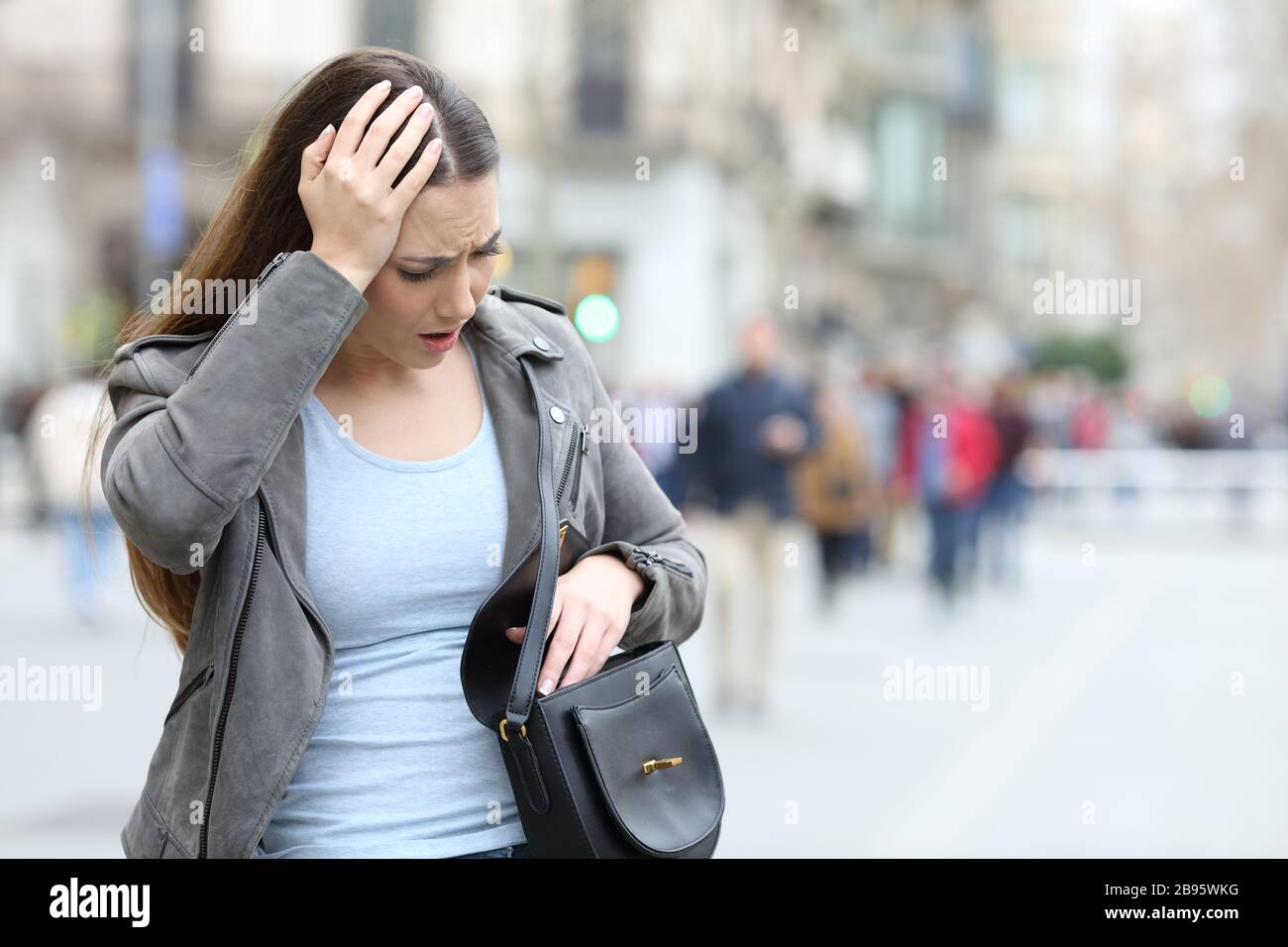 Ragazza preoccupata che guarda preoccupato all'interno della sua borsa a spalla su una strada della città Foto Stock