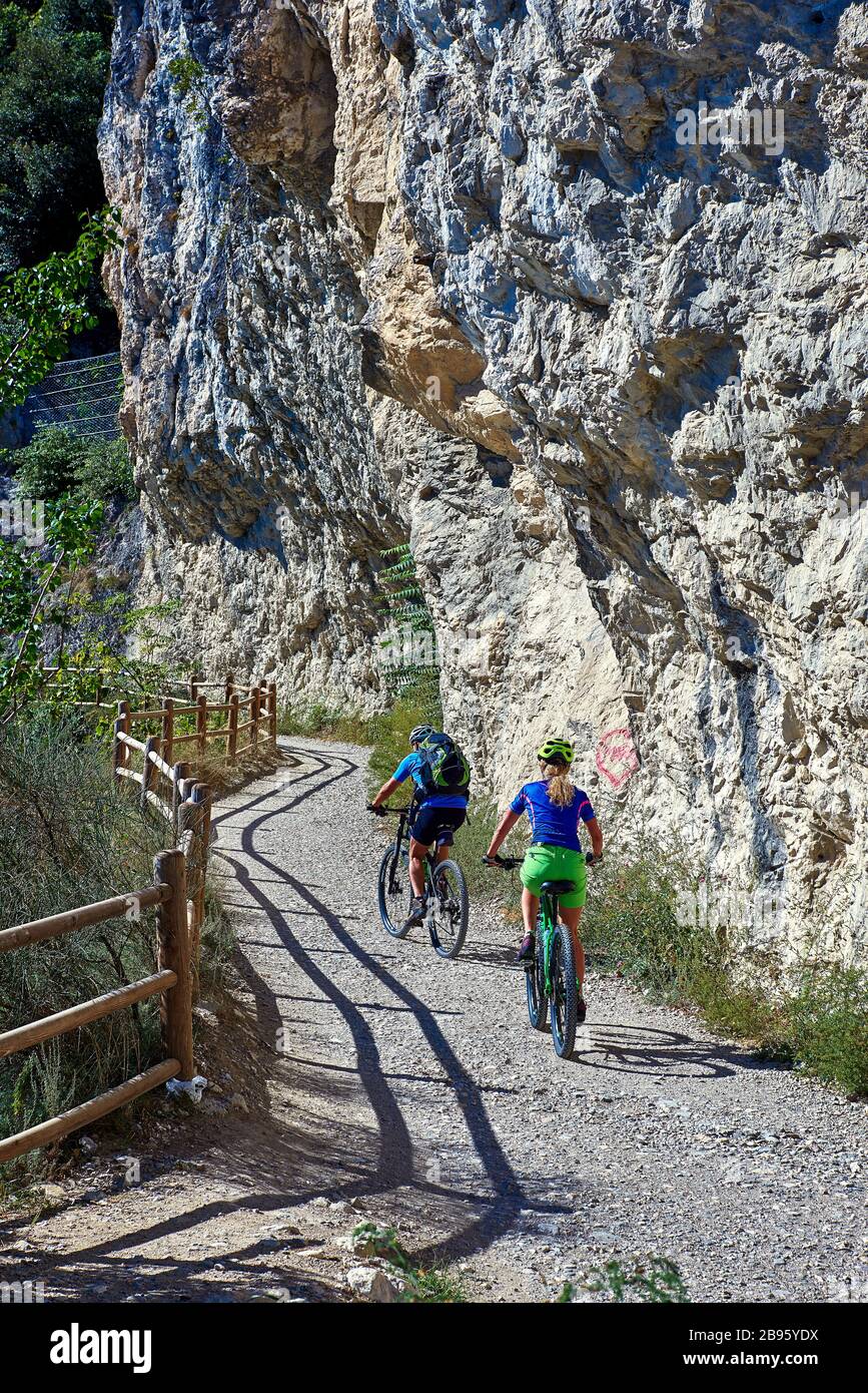 Ciclisti in bicicletta lungo la via ponale a Riva del Garda Foto Stock