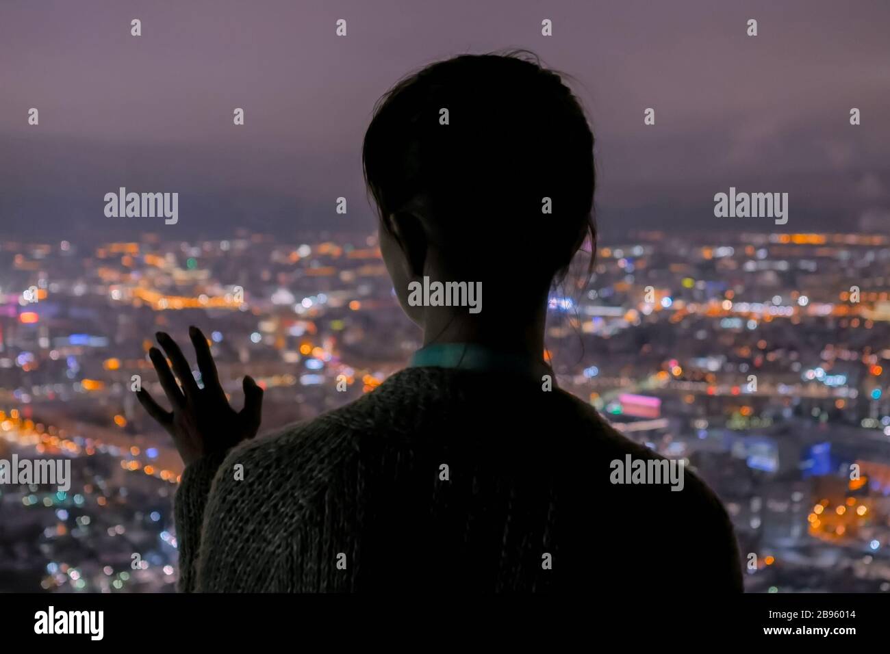 Malinconici donna che guarda la città di notte dal grattacielo Foto Stock