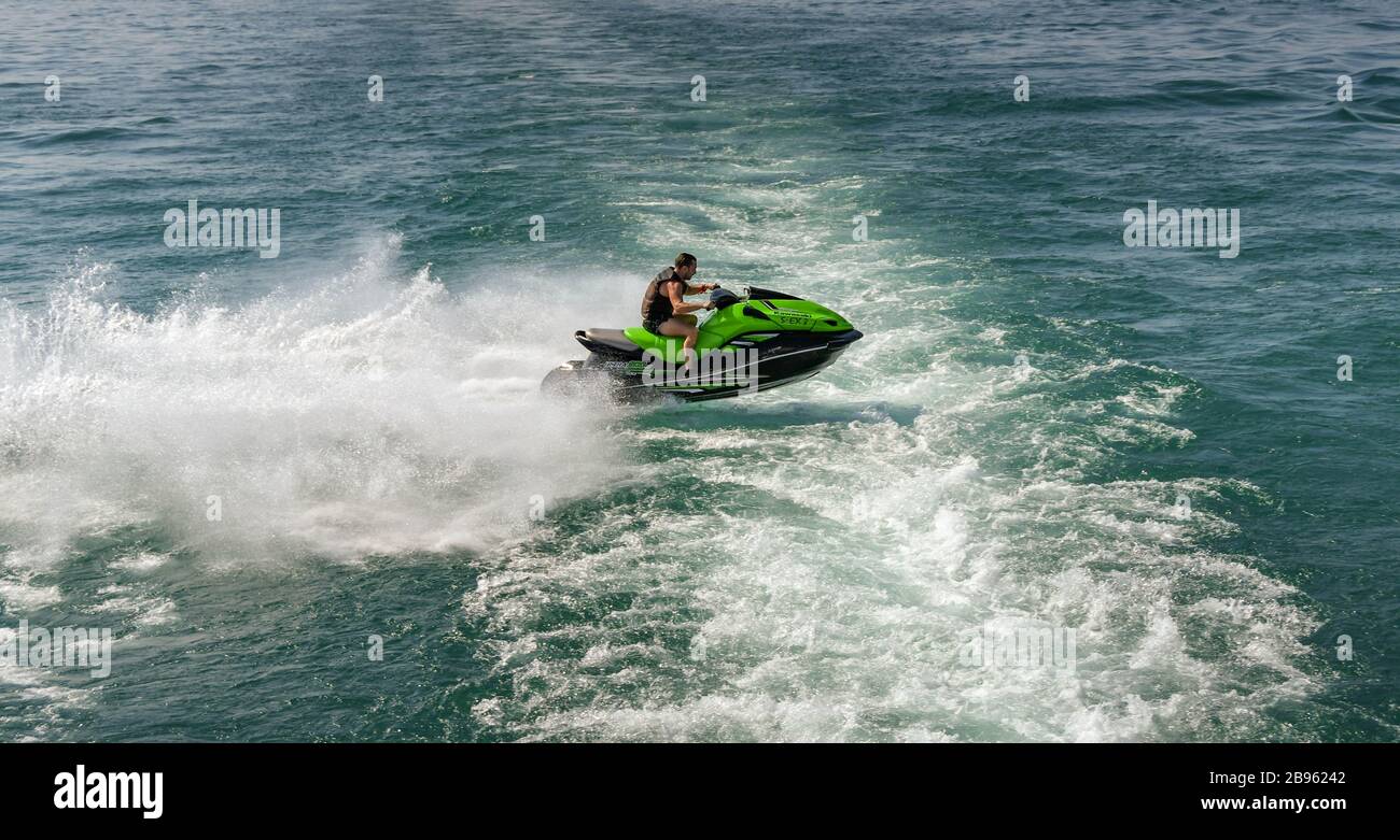LAGO DI GARDA, ITALIA - SETTEMBRE 2018: Persona a bordo di un veloce jet ski che salta onde sulla scia di un traghetto passeggeri sul Lago di Garda. Foto Stock