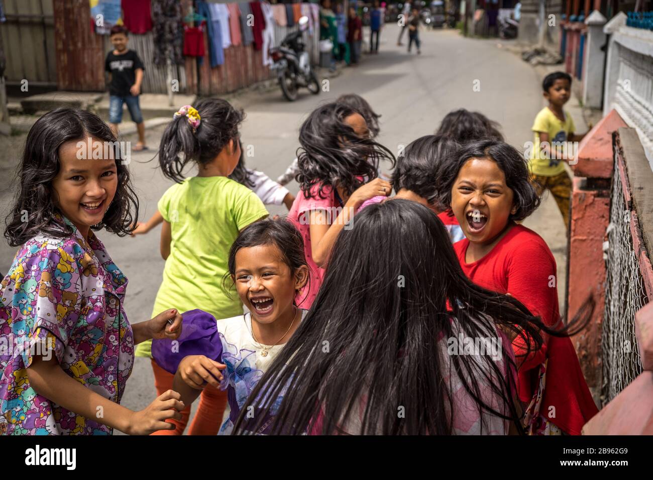 I bambini eccitati e impauriti di macchina fotografica che corrono via sulla strada della città di Panyambungan, Sumatra del Nord, Indonesia momento notevole per ricordare la squala urbana Foto Stock