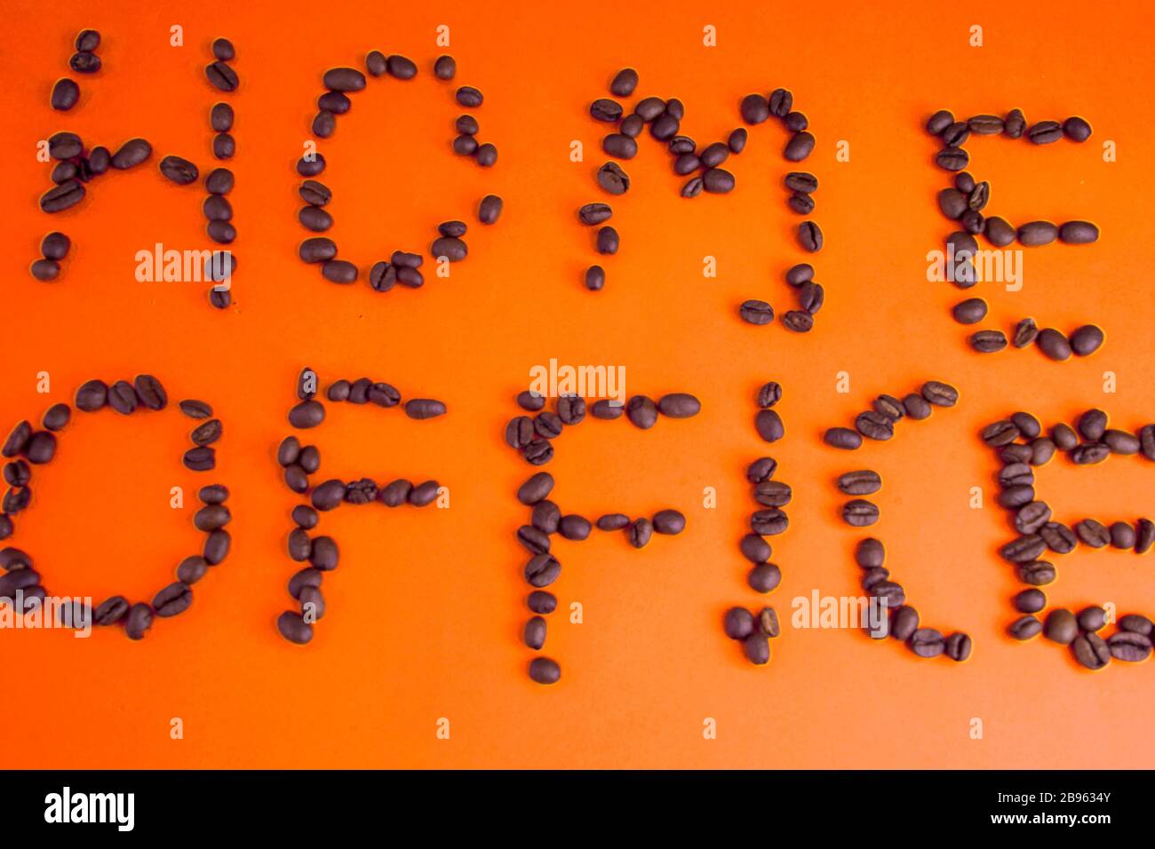 Home Office fatto di chicchi di caffè disposti su uno sfondo rosa Foto Stock