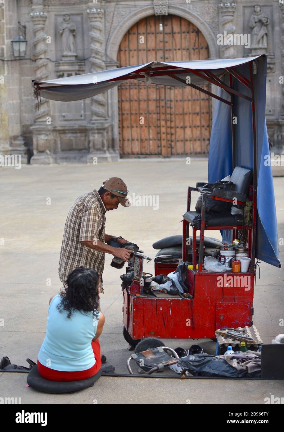 Un uomo brilla le scarpe di una donna da uno stand davanti al Templo de San Francisco de Asis. Foto Stock
