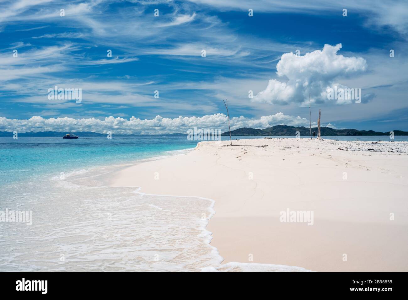 Solitaria spiaggia di sabbia bianca con oceano turchese e cielo blu con nuvole. Foto Stock
